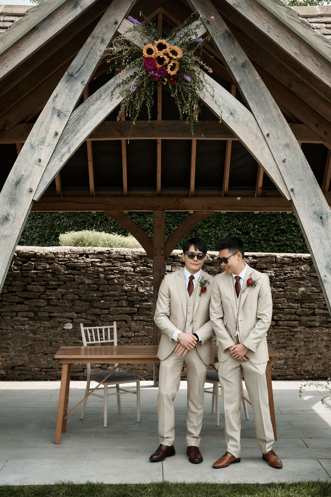 Two guys dressed in suits are standing in front of a wooden pavilion.