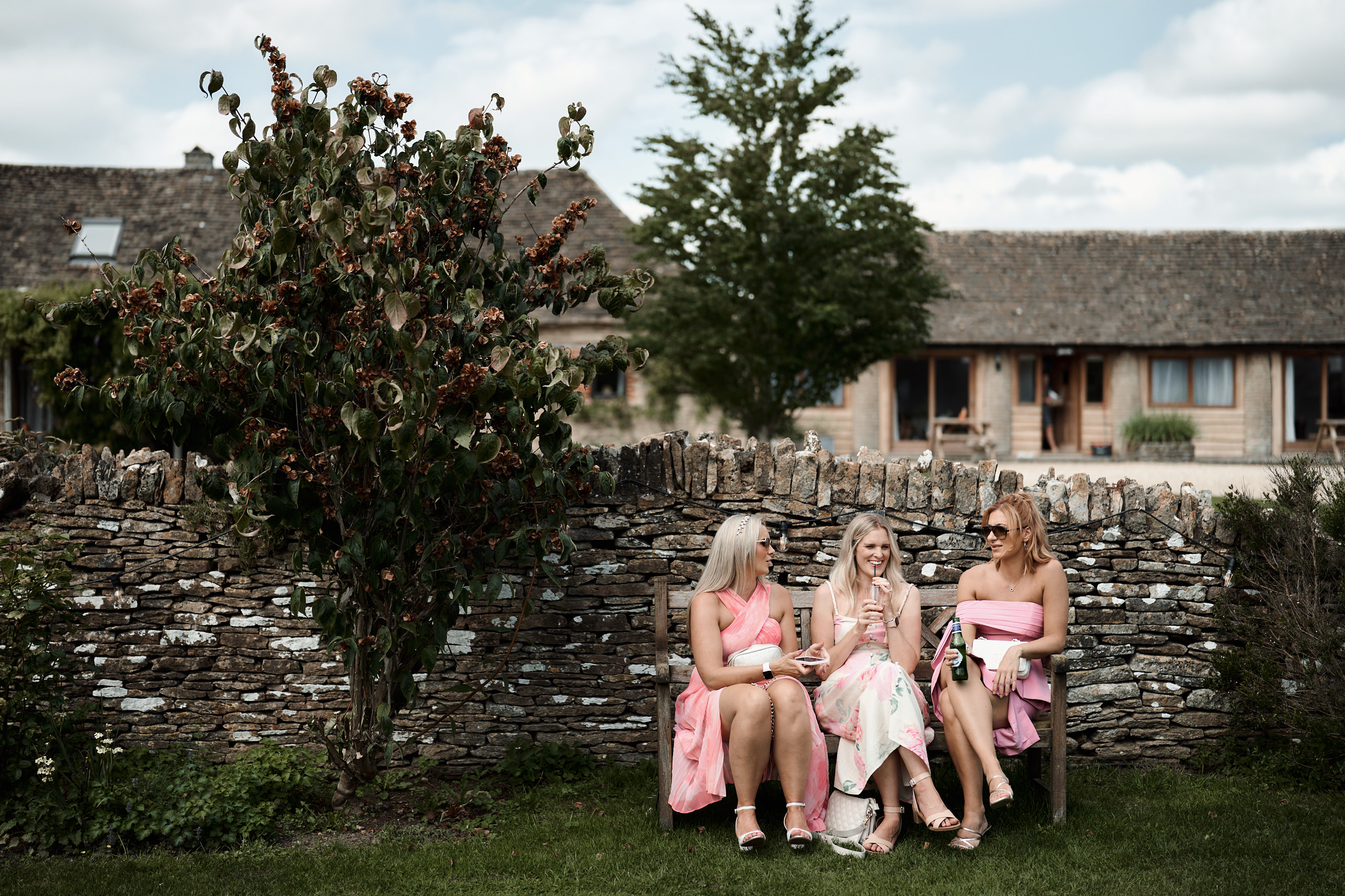 Four bridesmaids are chilling on a bench in front of a brick wall.