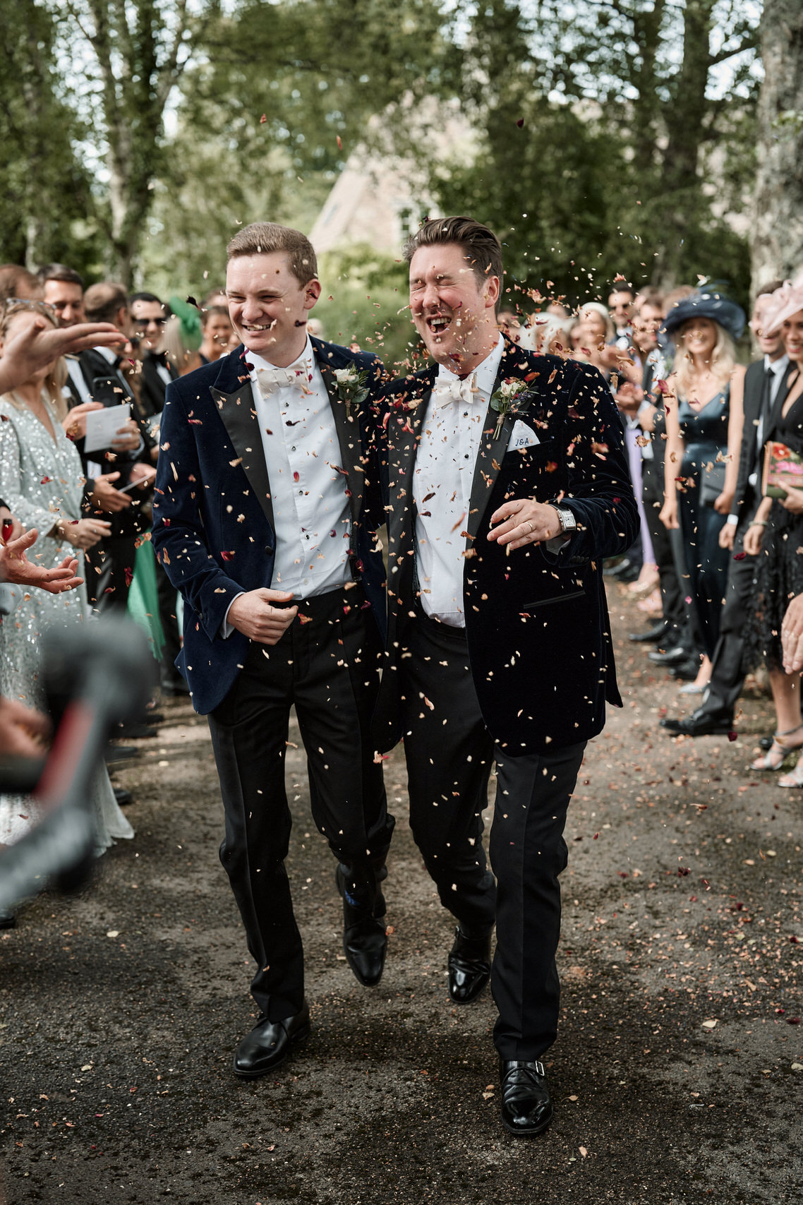 Two guys in suits are tossing confetti at each other.