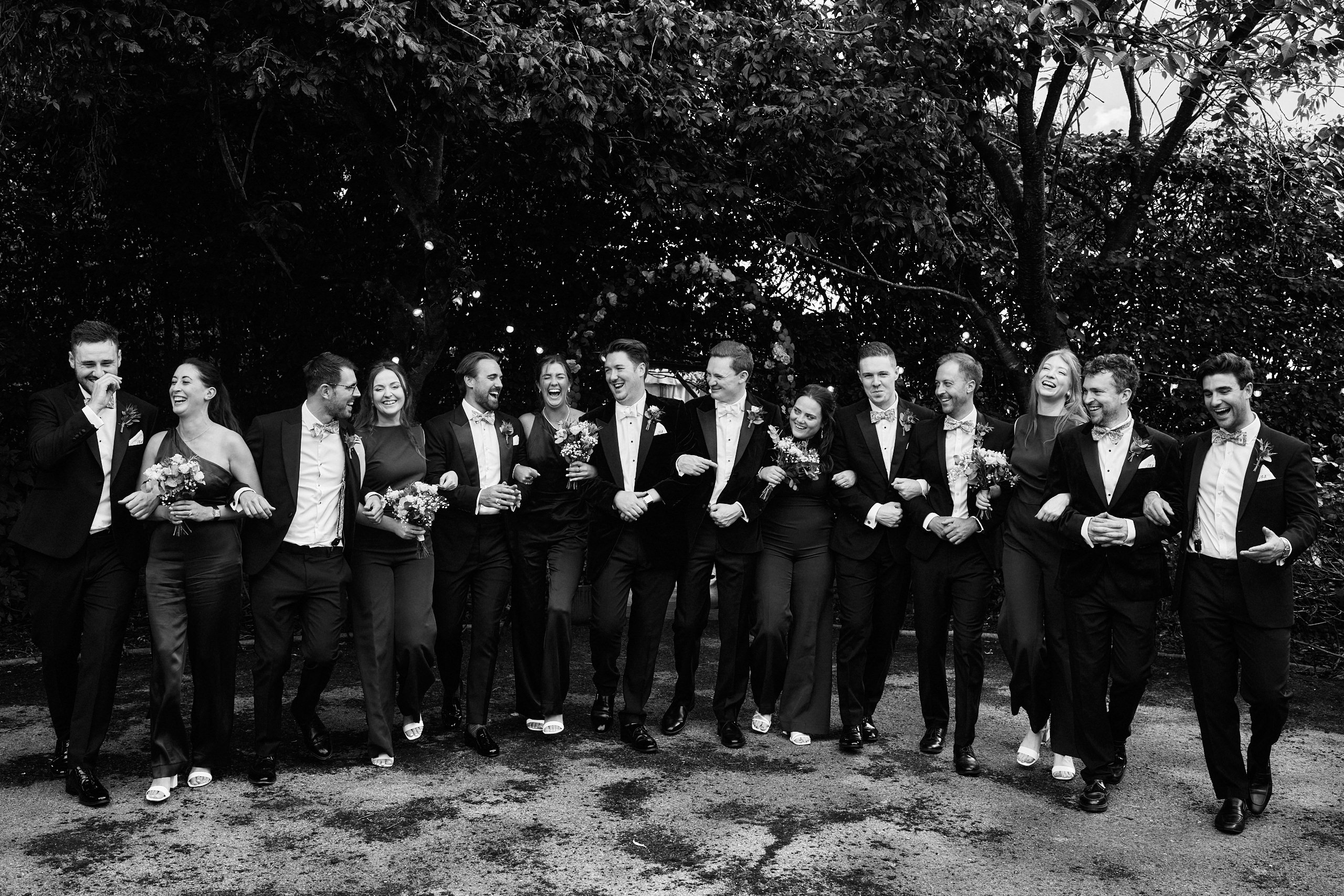 A black and white picture of a bunch of guys in a wedding party.