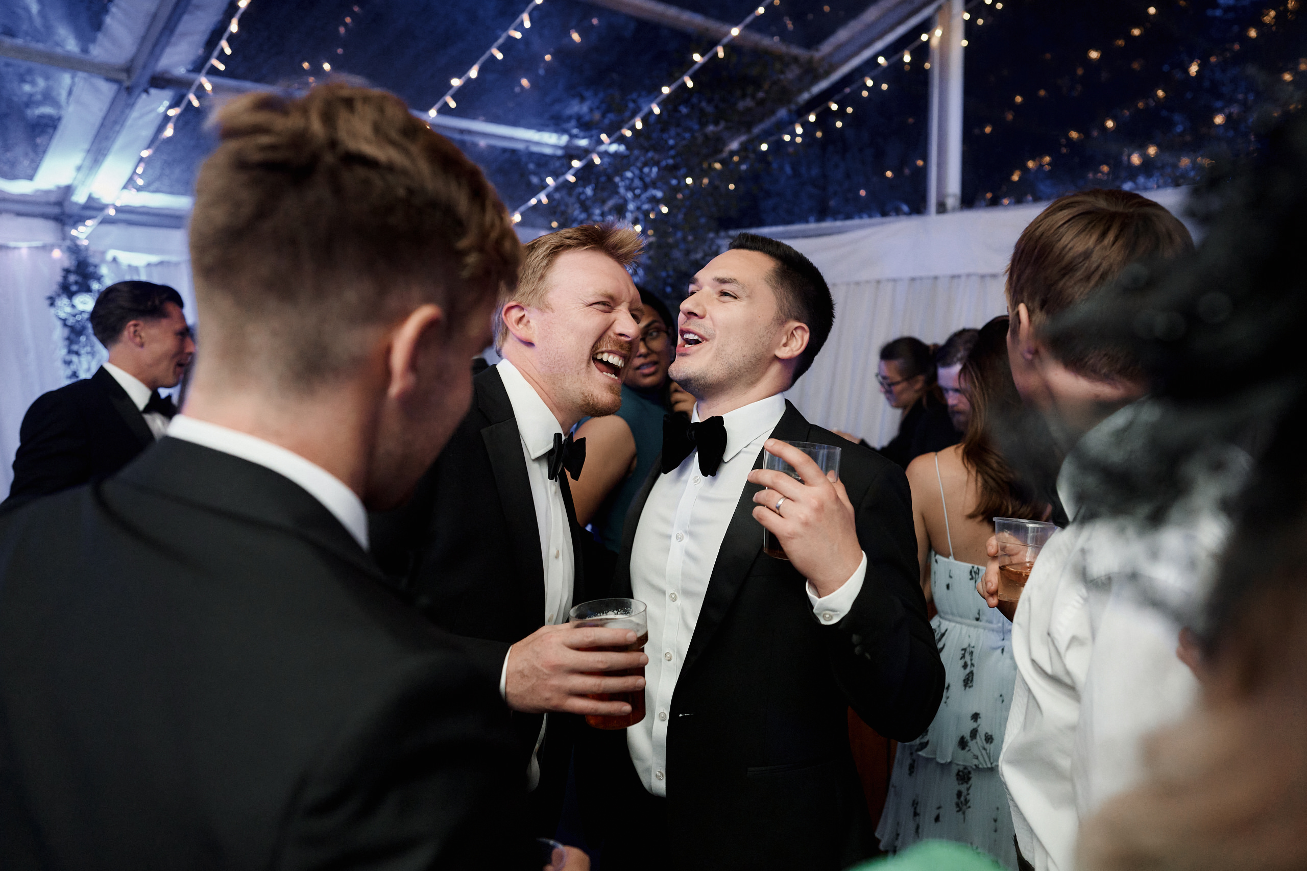 A bunch of guys in suits having a laugh at a party.