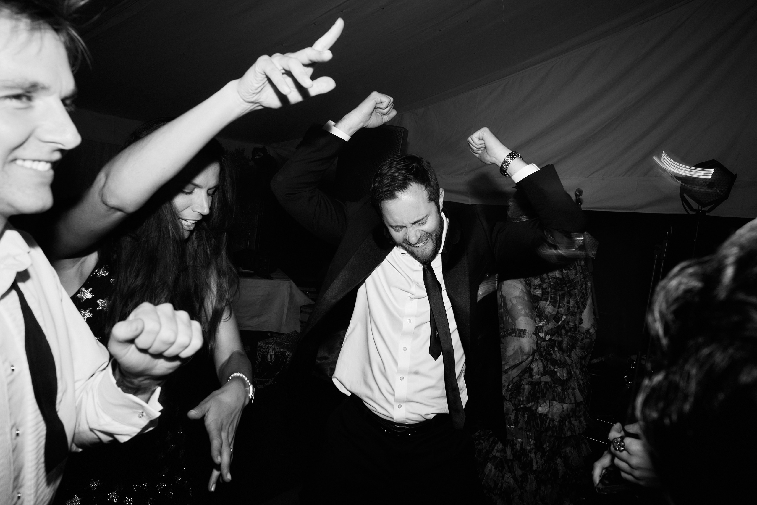 A grayscale picture of folks busting a move at a wedding.