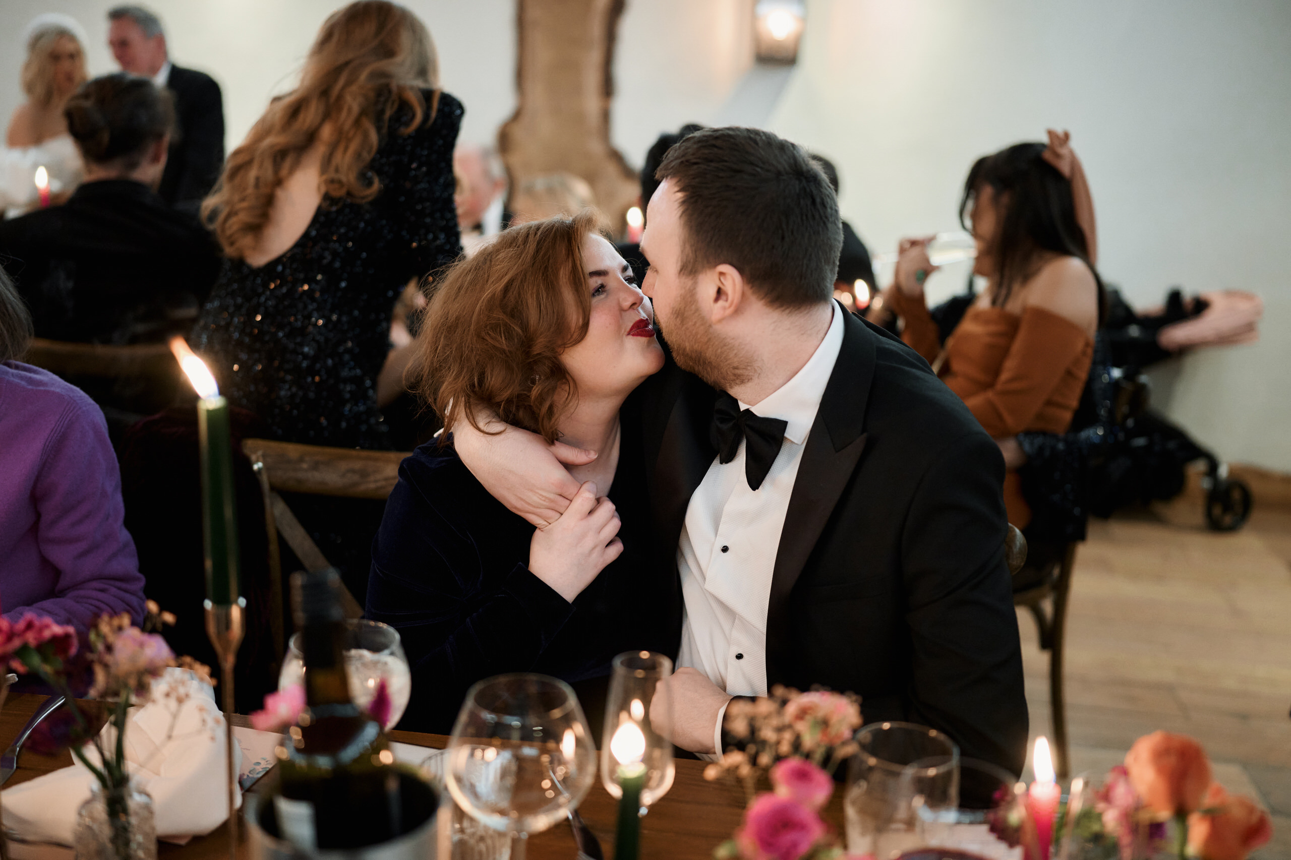 Two people kissing at a wedding party.