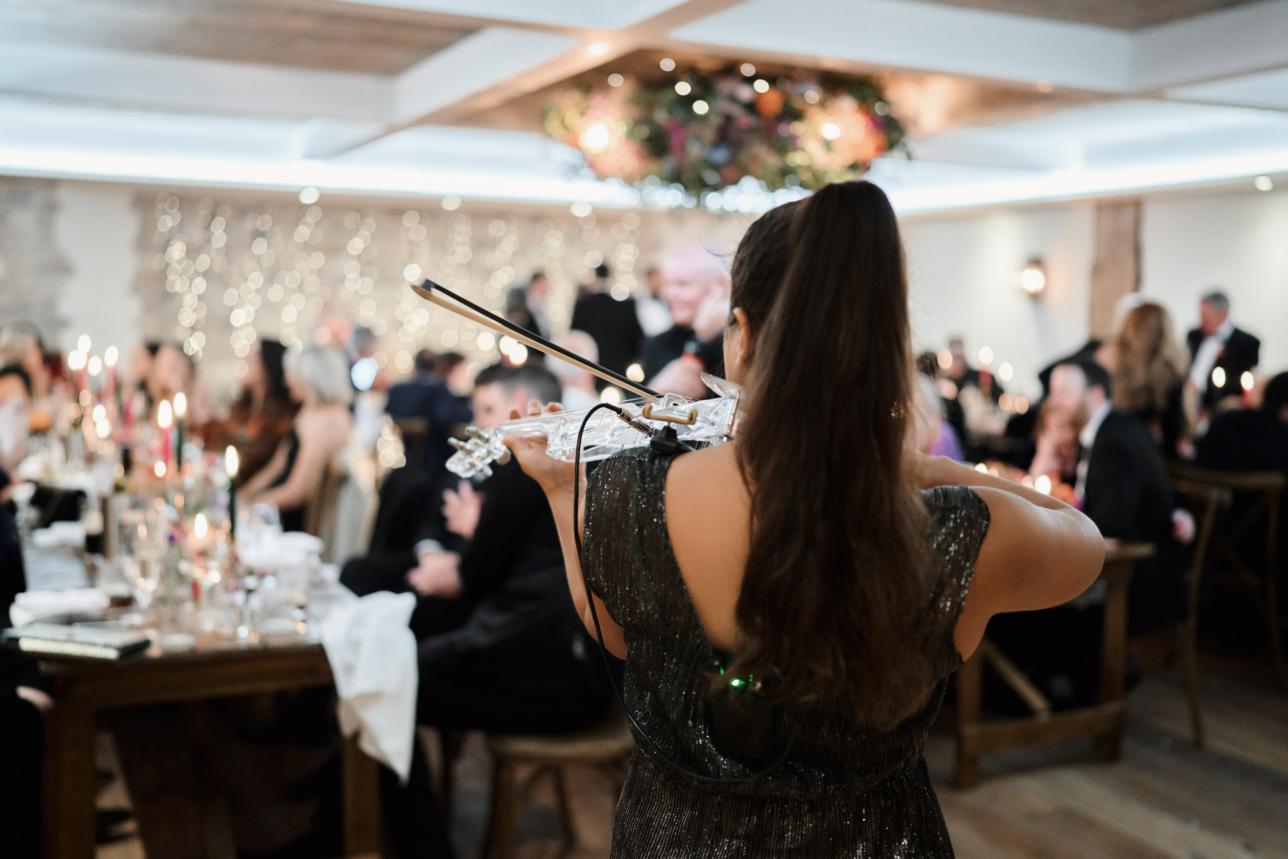 A lady is playing the violin at a wedding party.