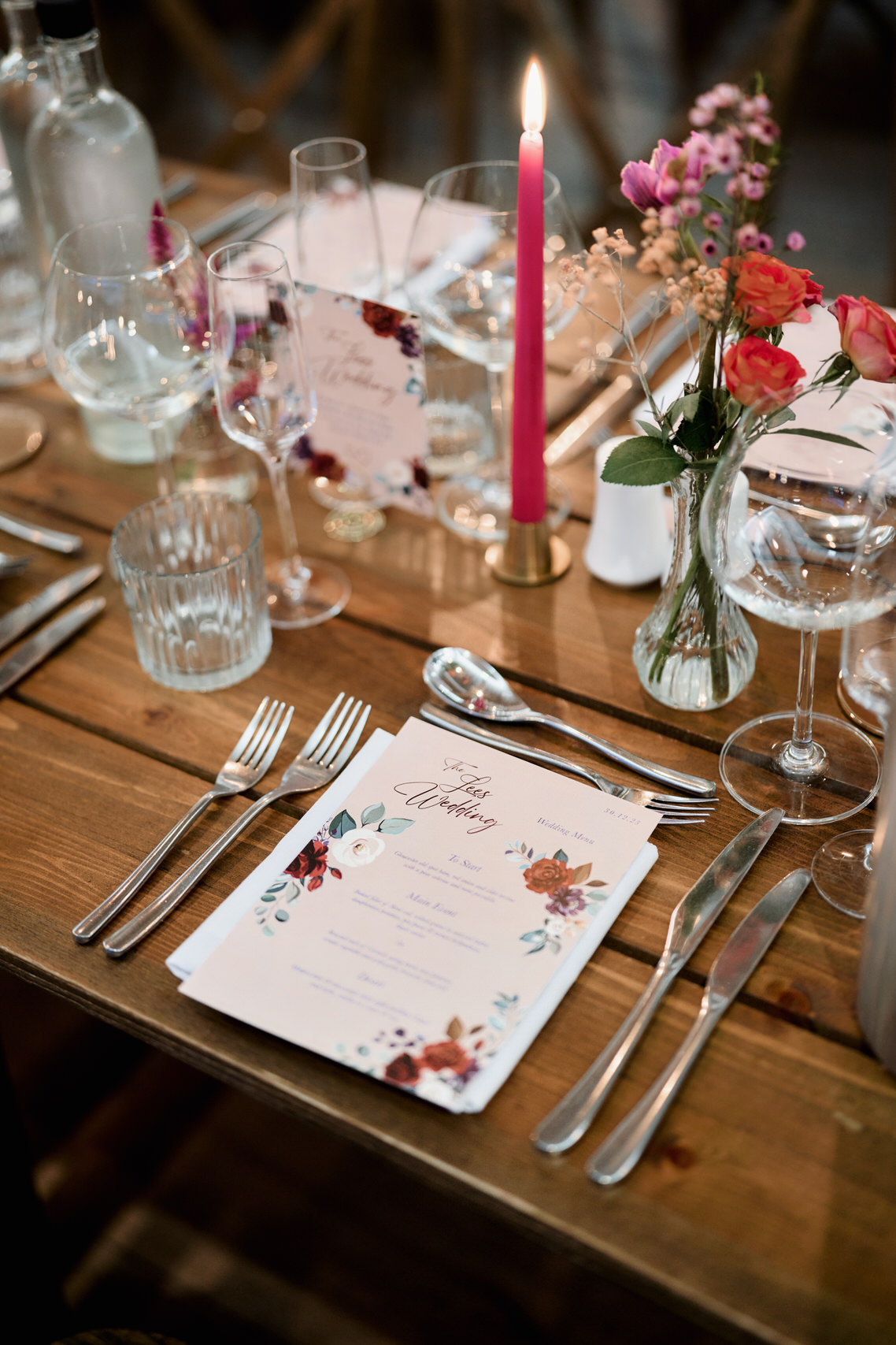 A dinner table set up with flowers and cutlery on a wooden table.