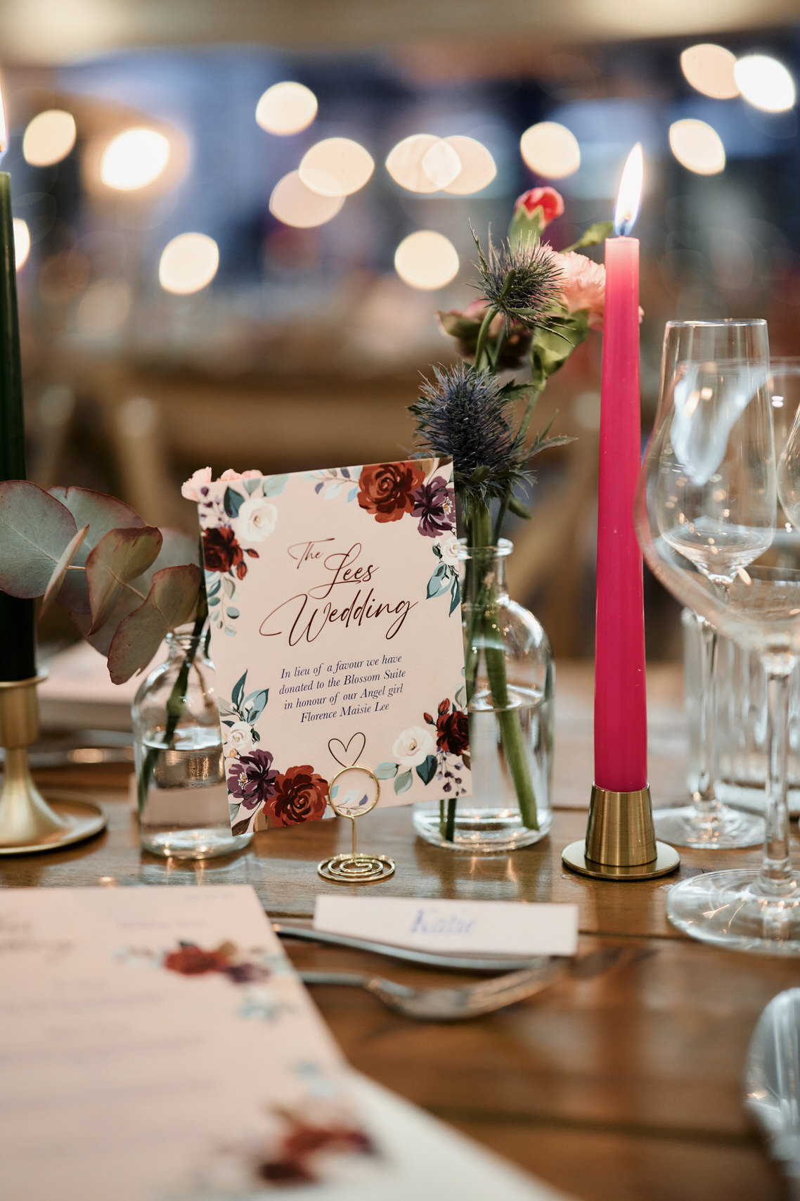 A dinner table setup with candles and a name card.