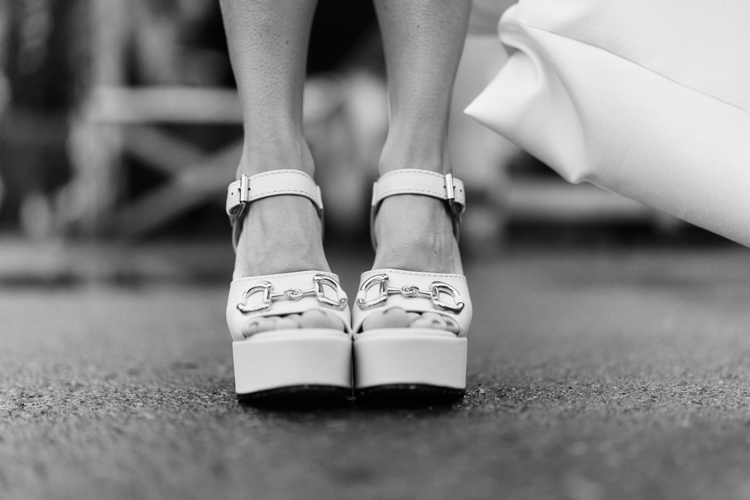 A black and white picture of a lady in white high-heeled shoes.