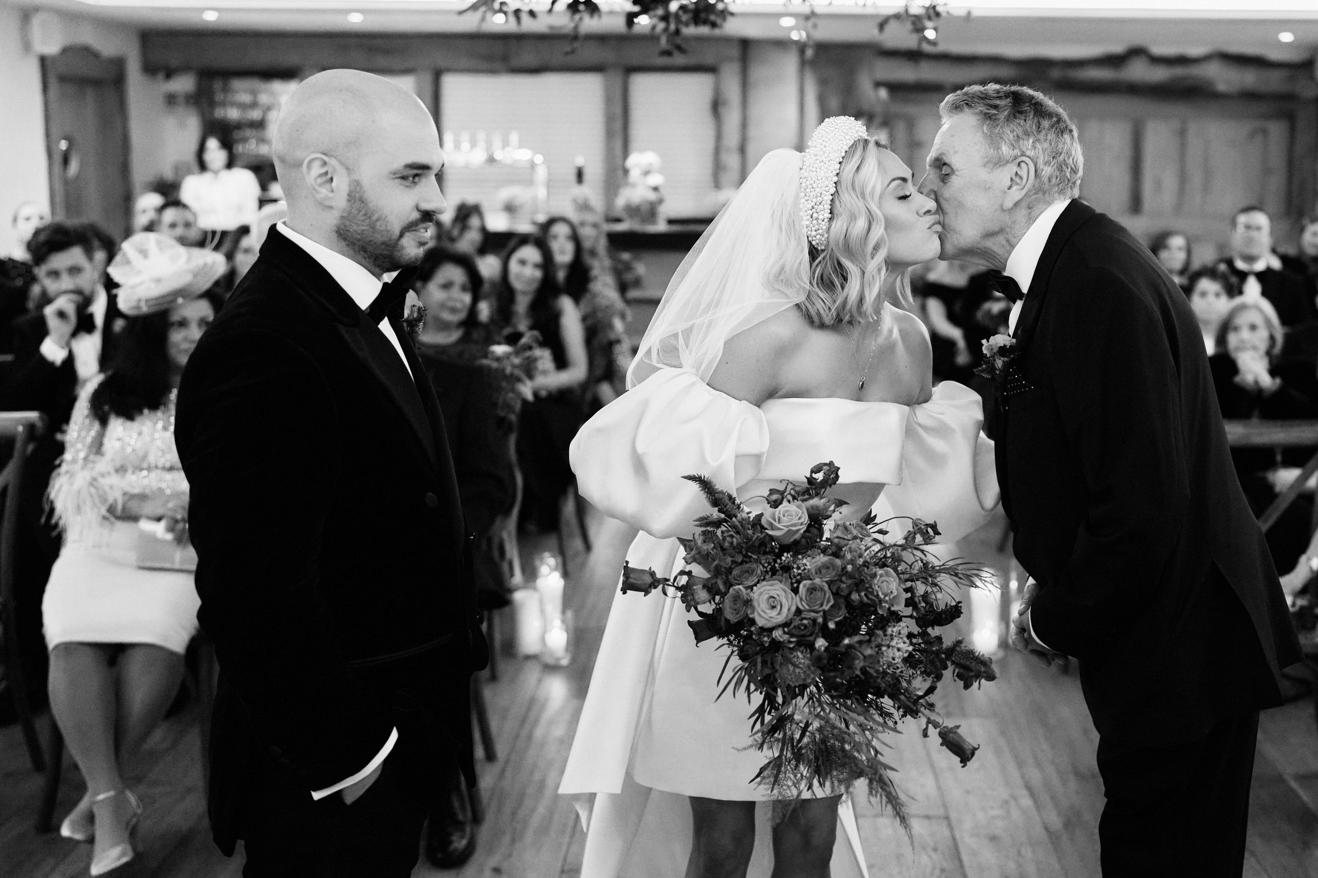 A bride kisses her dad during her wedding.