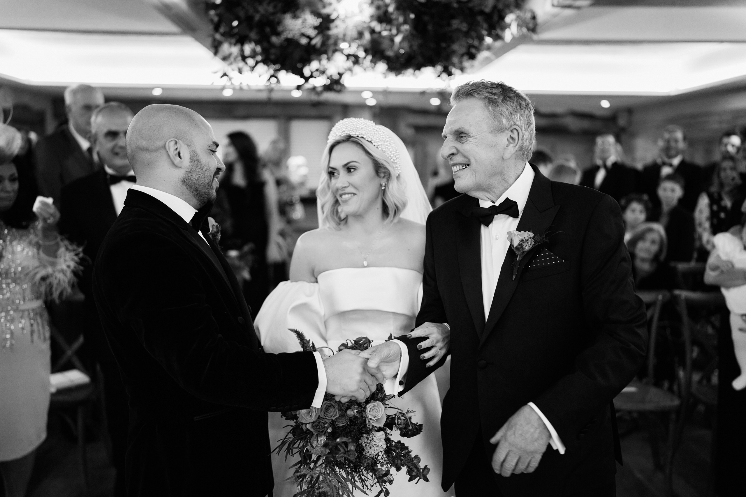 A black and white picture of a bride and groom going down the aisle.